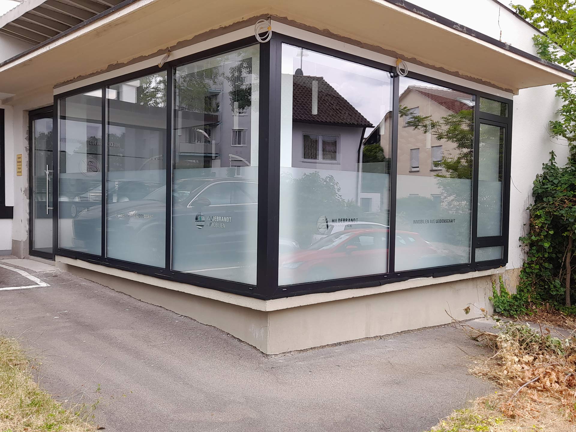 Ein modernes Gebäudeeck mit großen Glasfenstern und reflektierenden Oberflächen.