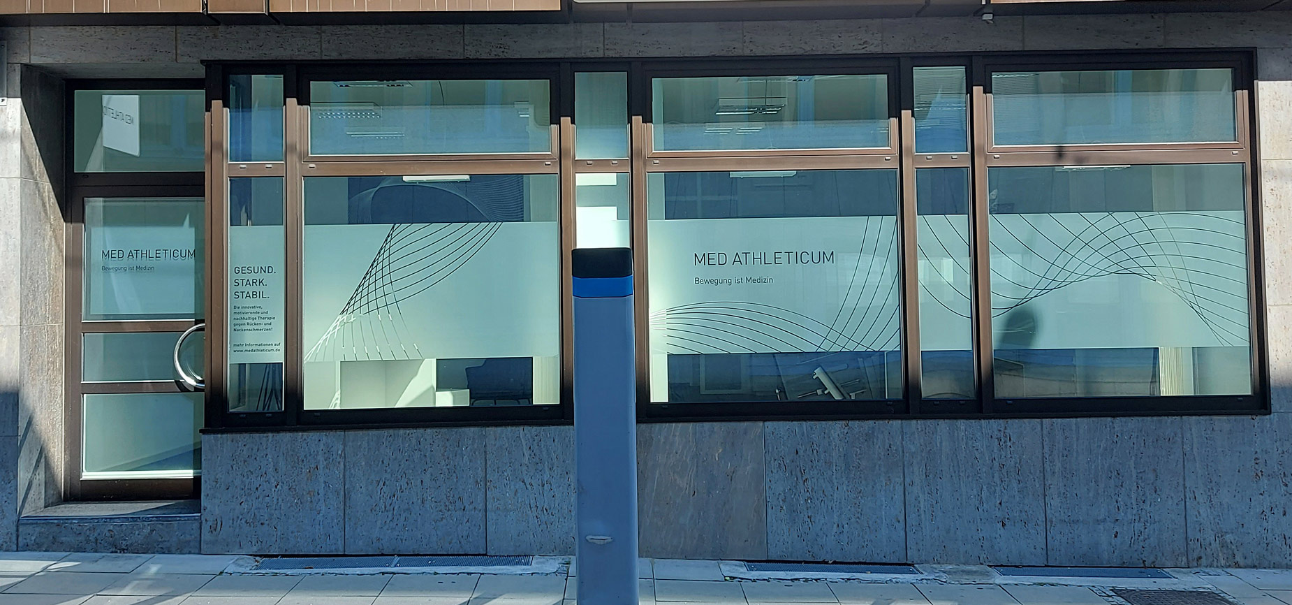 Fassade eines Gebäudes mit großen Fenstern und moderner Beschriftung in Blau.