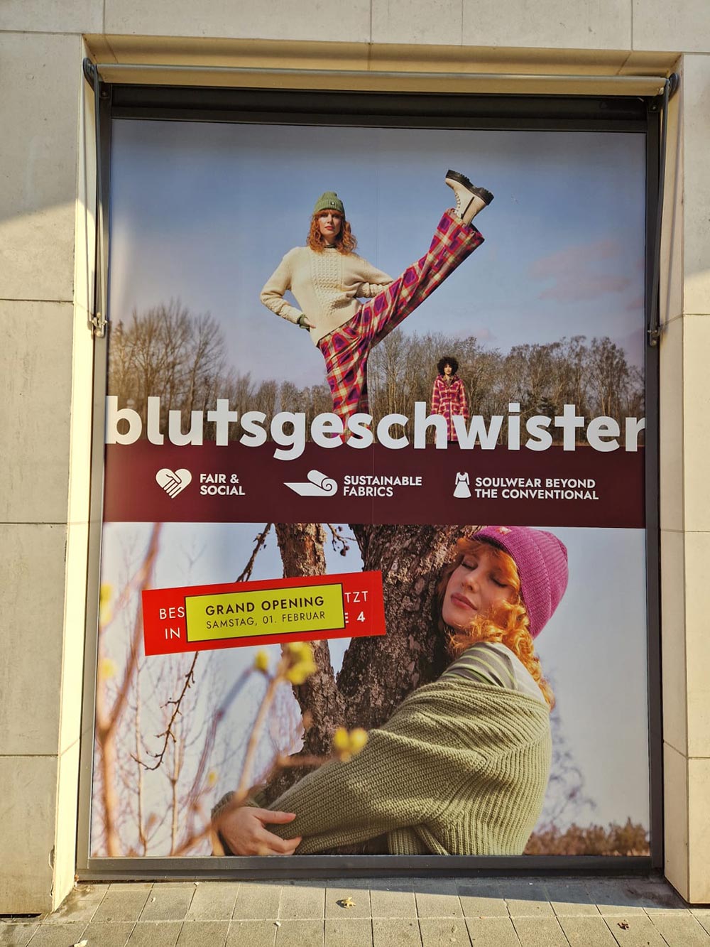 Frau laechelt, beiger Pullover, bunte Hose, hoher Kick, grosse Werbung