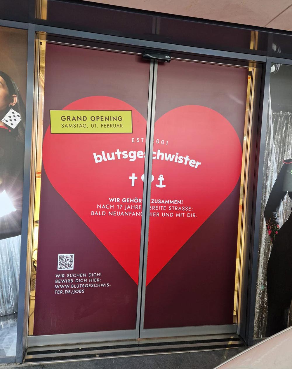 Rotes Herz mit Schriftzug blutgeschwister und Grand Opening Hinweis auf Tuer