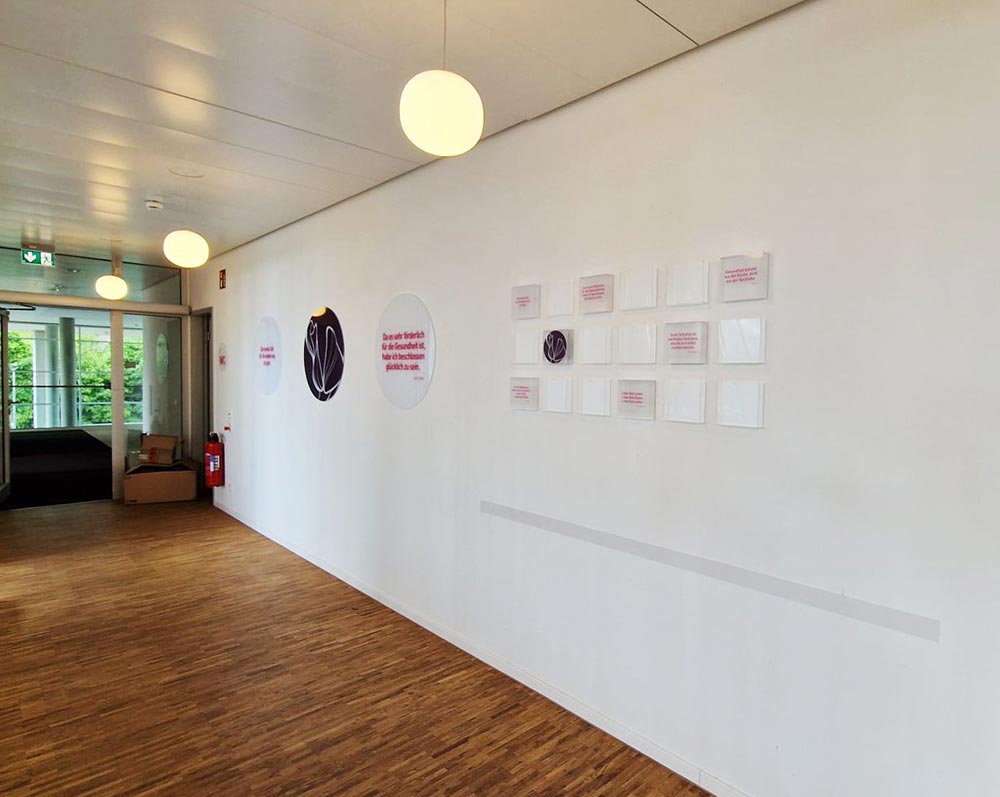 Leerer Flur mit Holzboden, weisser Wand und runden Deckenlampen
