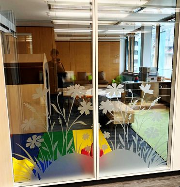Bueroraum hinter Glastuer mit Blumenmuster und dunkler Personensilhouette