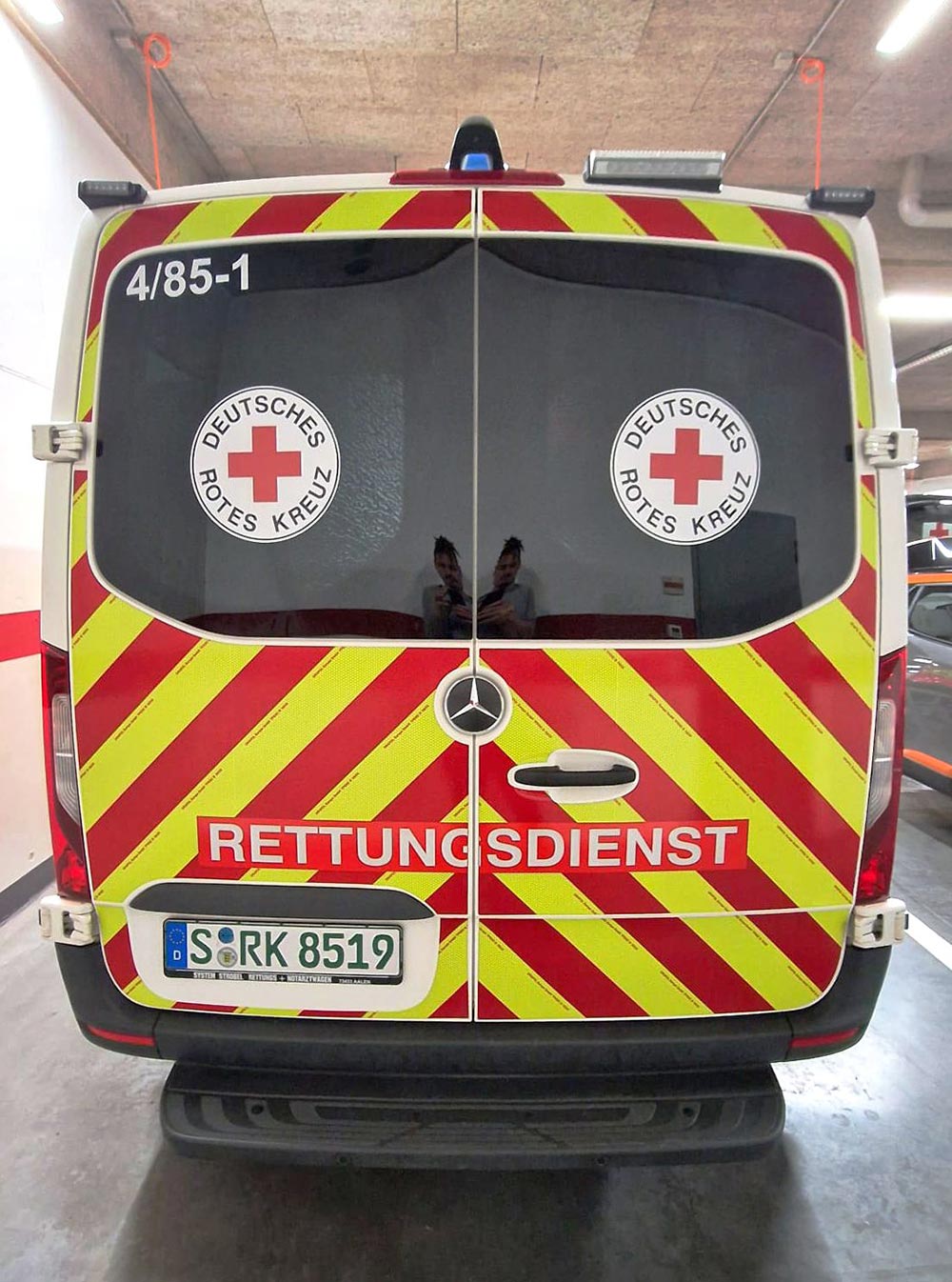 Roter Rettungswagen hinten mit ruhigem Look, gelbrote Streifen, Rotkreuz Logos