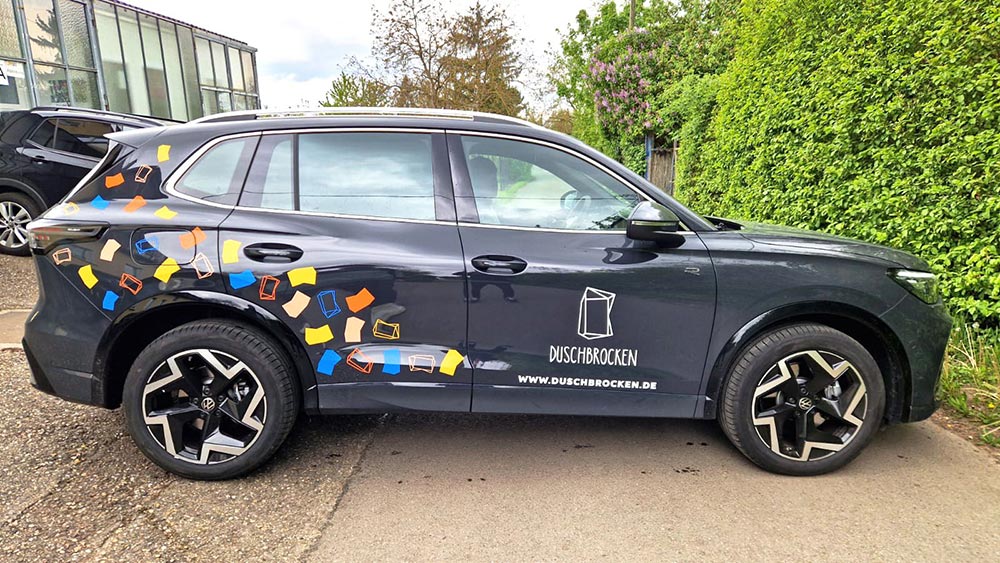 Schwarzer SUV mit bunten Umzugskartons und Duschbrocken Logo an der Seite